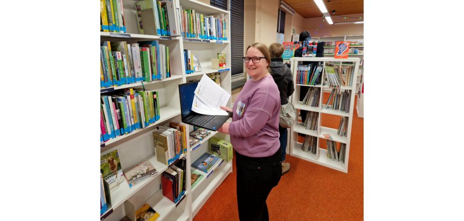 Franziska Huhnke mit einem Laptop in der Bibliothek und Antragsformularen