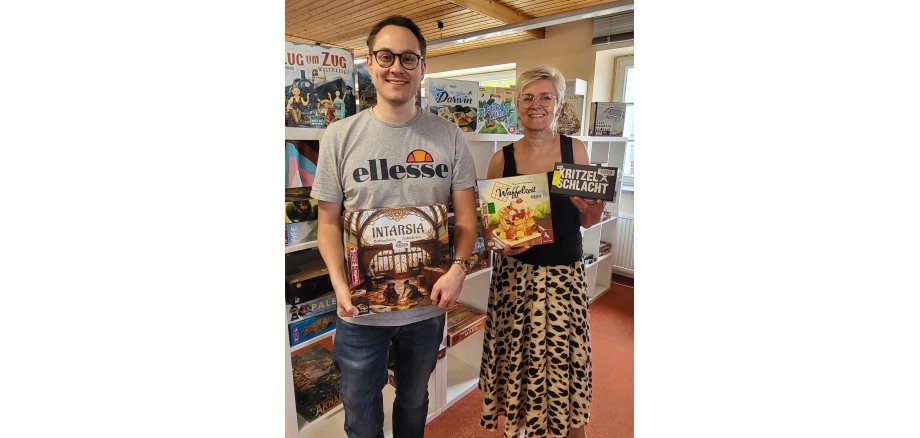 Philipp Helmers und Irmgard Weisner, Mitarbeiter*innen aus der Stadtbibliothek mit coolen Brettspielen