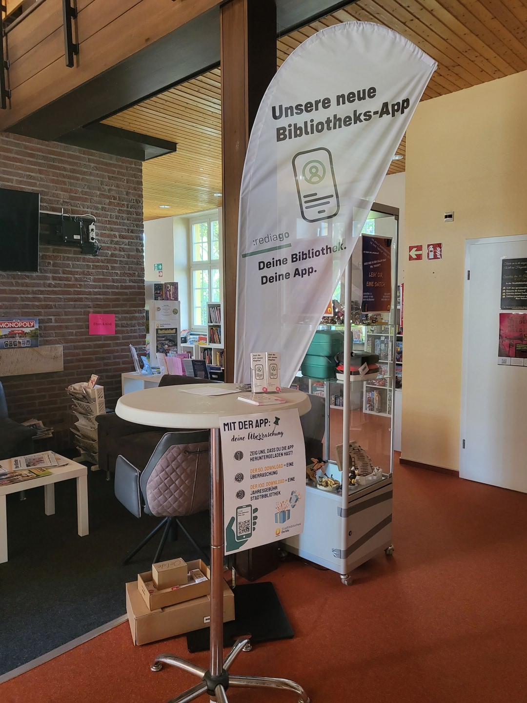 Ein Stehtisch im Erdgeschoss der Stadtbibliothek mit einer Werbefahne von :rediaGo der neuen Bibliotheksapp.
