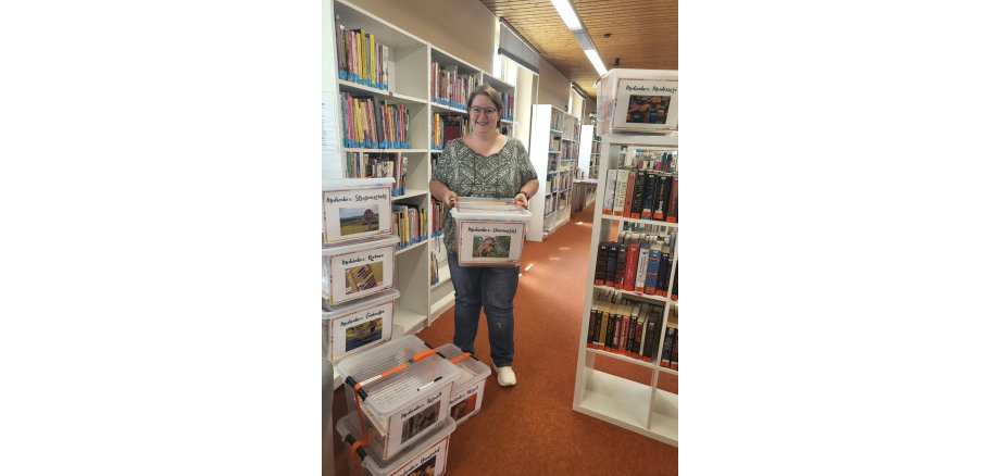 Auszubildende Ute Böse mit den acht Medienboxen der Stadtbibliothek 
