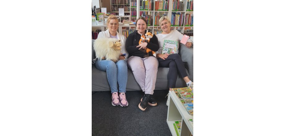 Birgitt Wunderlich, Franziska Huhnke und Irmgard Weisner Mitarbeiterinnen der Stadtbibliothek auf einem Sofa in der Kinderbibliothek zum Vorlesestart mit Bilderbuch und Co.