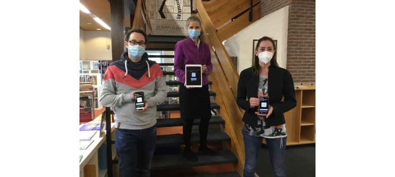 Bibliotheksmitarbeiter mit Handys, und Tablets auf einer Treppe in der Bibliothek